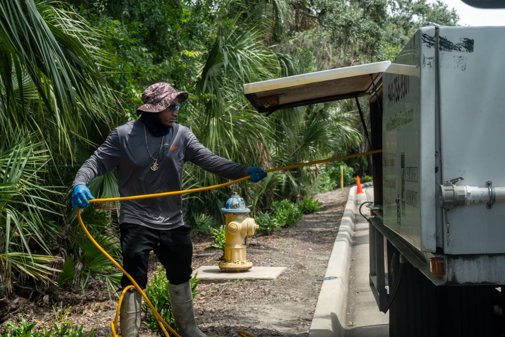 A GreenEdge staff member pulling a hose from a company truck in Sarasota. Our dedicated team utilizes this equipment to efficiently deliver water or other necessary substances to maintain the health and beauty of your landscape. Trust GreenEdge for expert irrigation services and reliable care for your outdoor spaces.